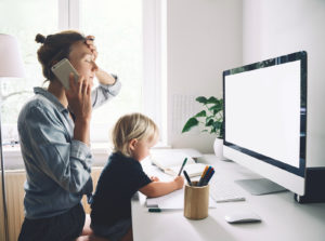 A woman sits at a computer with her toddler. She is looking forward to starting counseling for moms in Denver, CO with Hot Mess Moms online therapy in Colorado. Get support in Lakewood, Denver, Littleton, Morrison and beyond with an online therapist in Denver, CO.